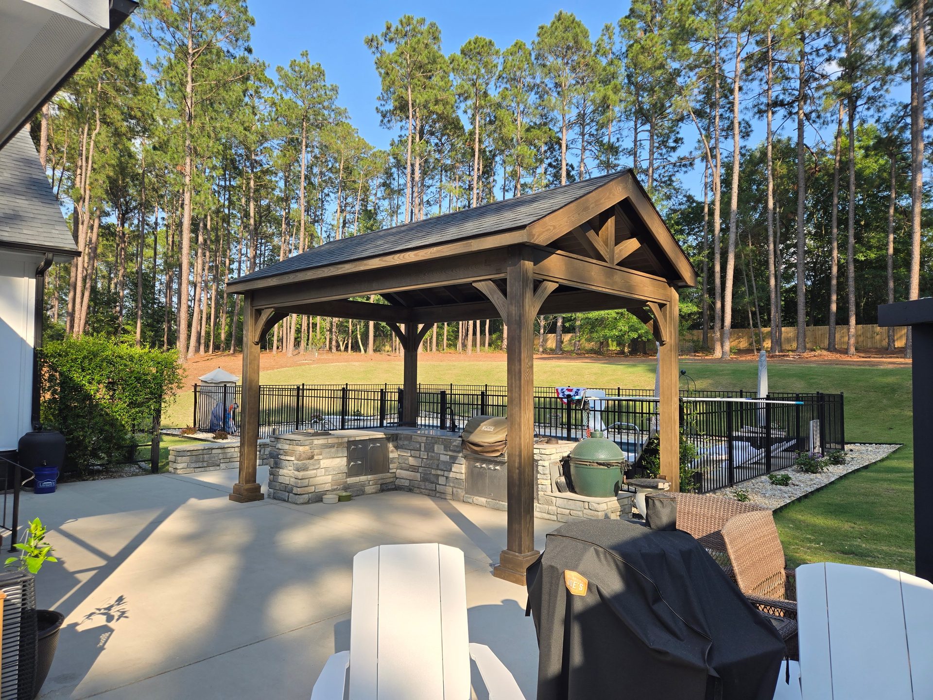 Front view of a heavy-timber gable pavilion with exposed truss over a stacked-stone outdoor kitchen