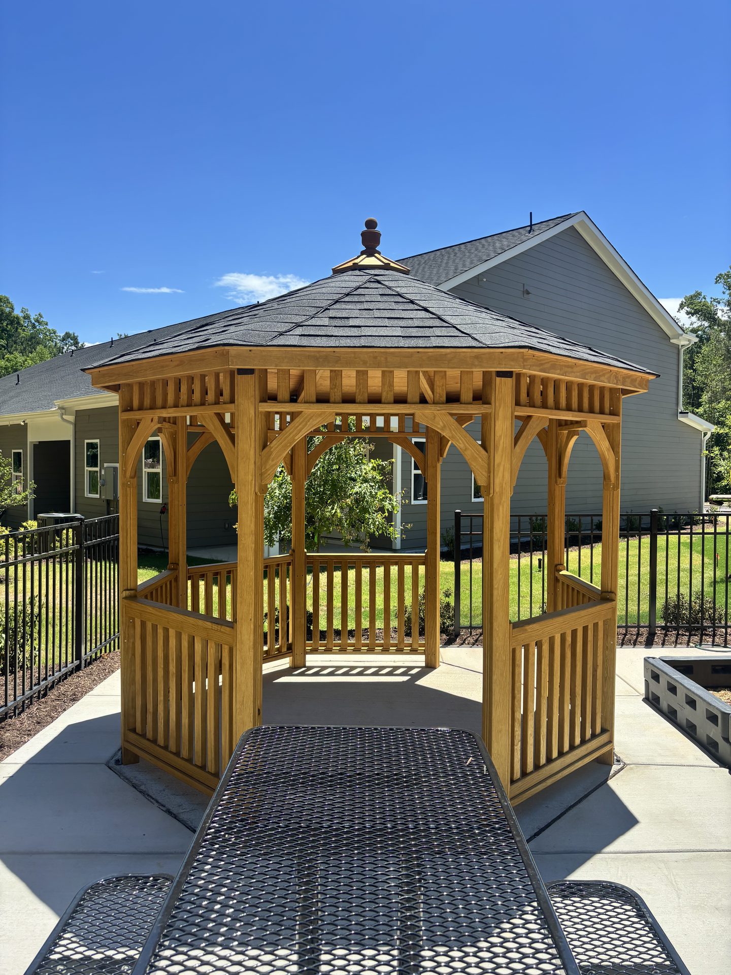 Stone kitchen island under a timber pavilion overlooking a pool with loungers